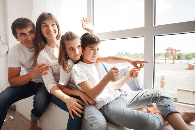 Gelukkige familiezitting op vensterbank en thuis het spelen