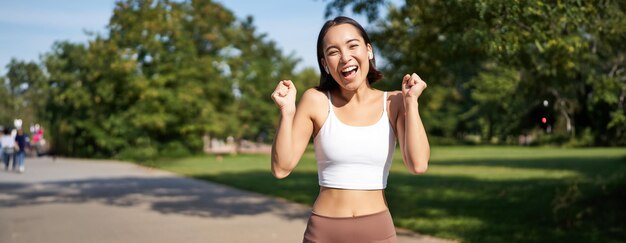 Gelukkige fitness meisje bereiken doel finish marathon lopen met de handen omhoog vieren de overwinning terwijl