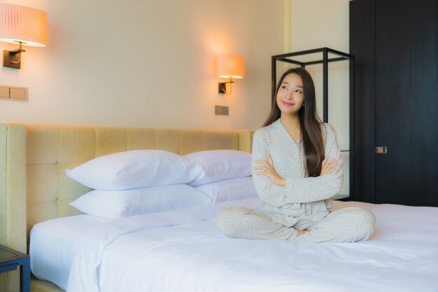 Gelukkige glimlach van de portret ontspant de mooie jonge aziatische vrouw op bed