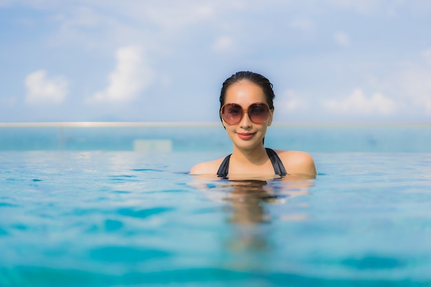 Gelukkige glimlach van portret ontspant de mooie jonge aziatische vrouwen openlucht zwembad in toevlucht