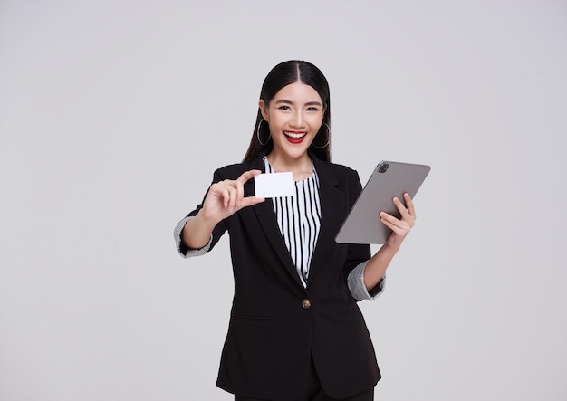 Gelukkige glimlachende Aziatische zakenvrouw in pak die een creditcard presenteert voor online betaling