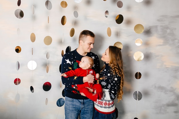 Gelukkige glimlachende familie bij studio op achtergrond van de kerstboom met gift