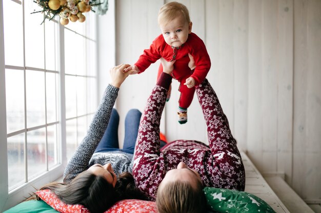 Gelukkige glimlachende familie bij studio op achtergrond van de Kerstboom met gift