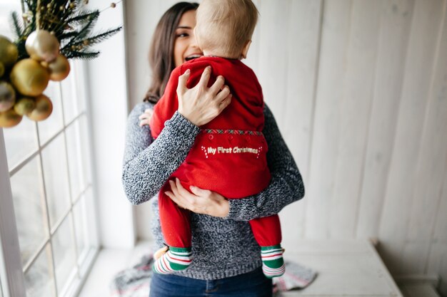 Gelukkige glimlachende familie bij studio op achtergrond van de Kerstboom met gift