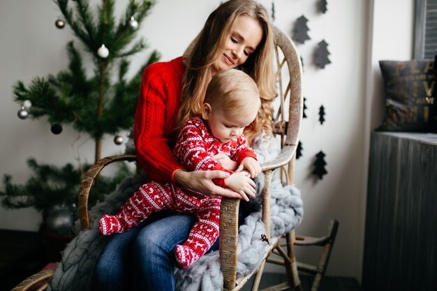 Gelukkige glimlachende familie bij studio op achtergrond van de Kerstboom met gift