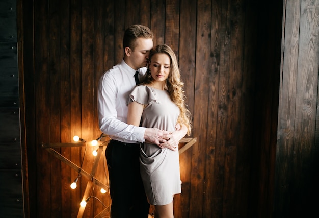 Gelukkige glimlachende familie bij studio op achtergrond van de Kerstboom met gift