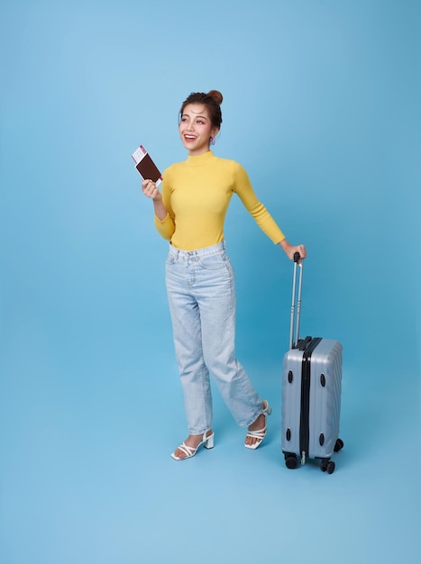 Gelukkige glimlachende jonge Aziatische toeriste met een paspoortticket en bagage die gaat reizen