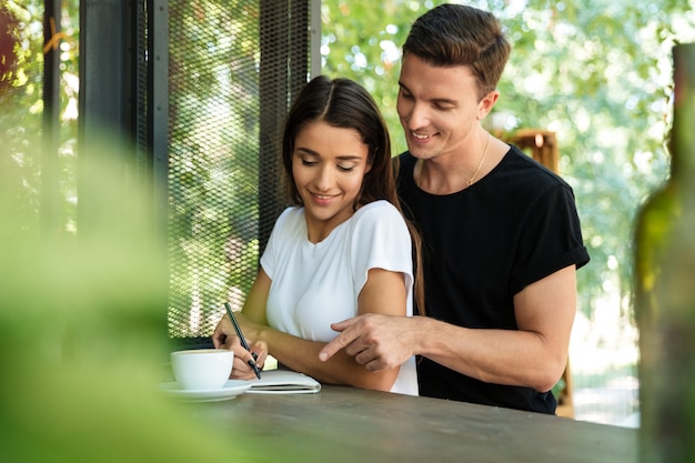 Gelukkige glimlachende vrouw die nota's in een handboek maakt