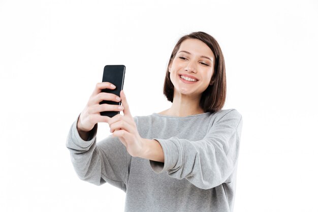 Gelukkige glimlachende vrouw die selfie op mobiele telefoon