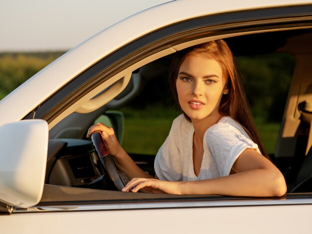 Gelukkige glimlachende vrouw in de auto die uit venster kijkt.