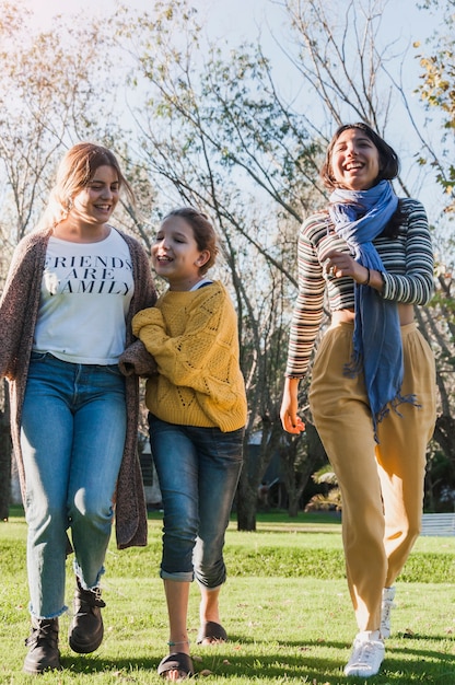 Gratis foto gelukkige glimlachende zusters die samen in park lopen