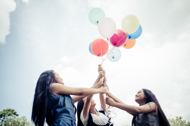 Gelukkige groep meisje vrienden hand met veelkleurige ballonnen