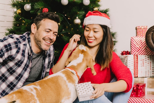 Gelukkige het lachen paar het vieren Kerstmis met hond