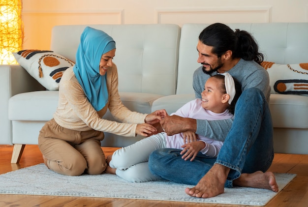 Gelukkige islamitische familie zittend op de vloer volledig schot