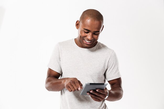 Gelukkige jonge Afrikaanse mens die tabletcomputer met behulp van.