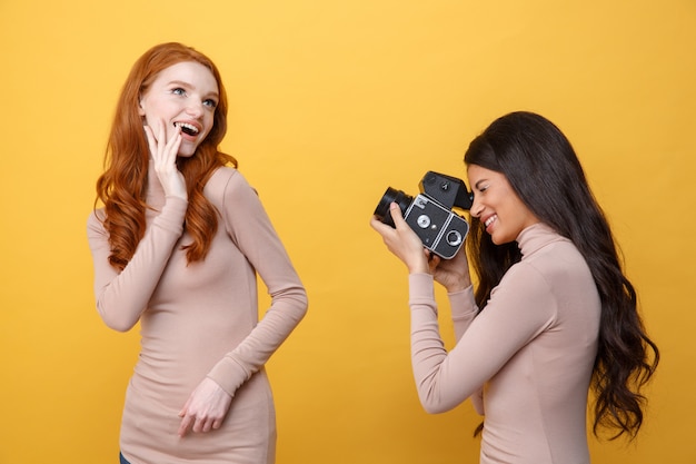 Gelukkige jonge Afrikaanse vrouw die roodharigedame fotografeert