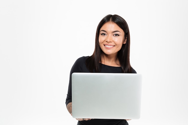 Gelukkige jonge Aziatische dame die door laptop computer babbelt