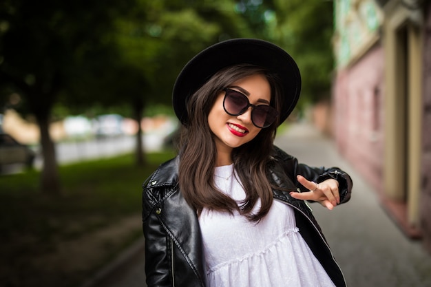 Gelukkige jonge Aziatische vrouw die selfie met vredesteken nemen op stadsstraat.