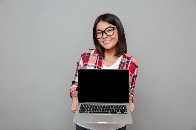 Gelukkige jonge Aziatische vrouw die vertoning van laptop computer toont.