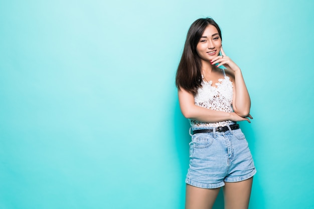 Gelukkige jonge Aziatische vrouw die zich op groene muur bevindt