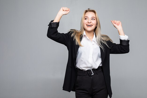 Gelukkige jonge bedrijfsvrouw die winnaargebaar doet, die ogen het gesloten stellen geïsoleerd houdt