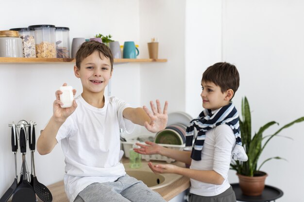 Gelukkige jonge geitjes die hun schone handen tonen terwijl het houden van zeep