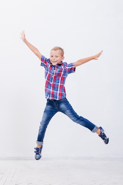 Gratis foto gelukkige jonge jongen die op wit springt