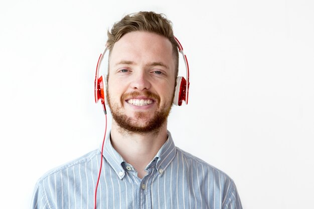 Gratis foto gelukkige jonge man luisteren naar muziek in de koptelefoon