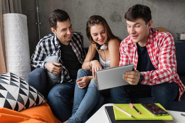 Gelukkige jonge mensen met behulp van tablet, studenten leren, plezier hebben, vriendenfeestje thuis, hipster bedrijf samen, twee mannen een vrouw, glimlachen, positief, online onderwijs