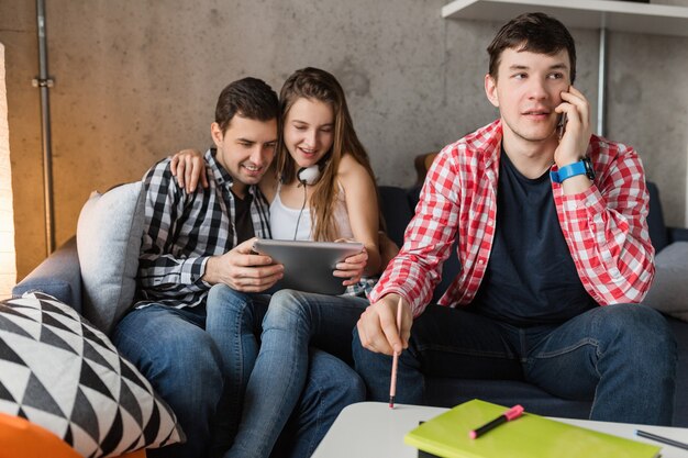 Gelukkige jonge mensen met behulp van tablet, studenten leren, plezier maken, vriendenfeestje thuis, hipster bedrijf samen, twee mannen een vrouw, glimlachen, positief, online onderwijs, man praten over de telefoon