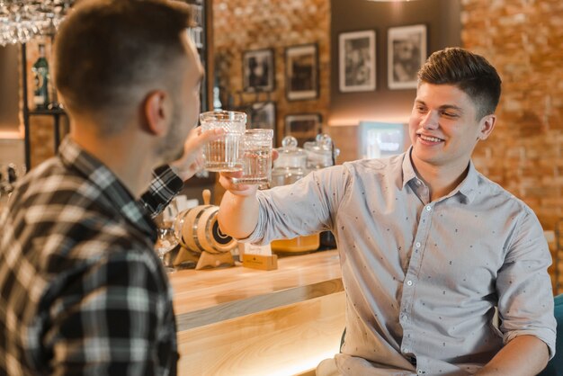 Gelukkige jonge mensen roosterende glazen cocktail bij restaurant