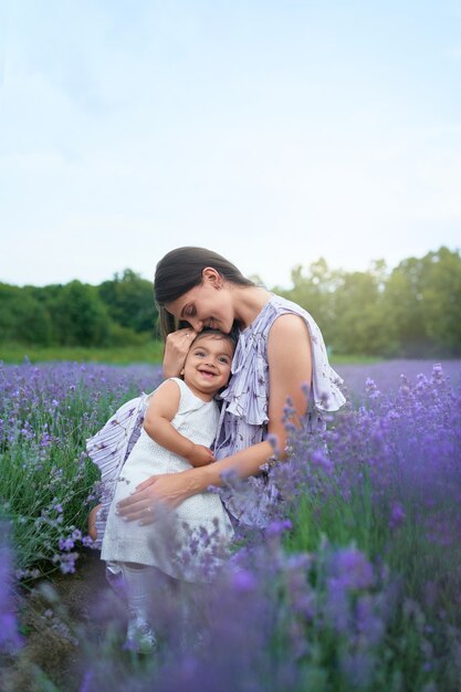 Gelukkige jonge moeder die kind knuffelt in lavendelveld