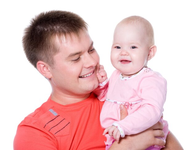 Gelukkige jonge vader die met aantrekkelijke glimlach zijn baby vasthoudt