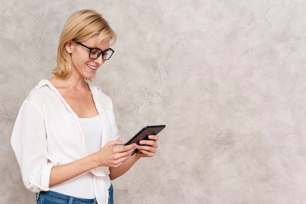 Gratis foto gelukkige jonge vrouw die een tablet houdt