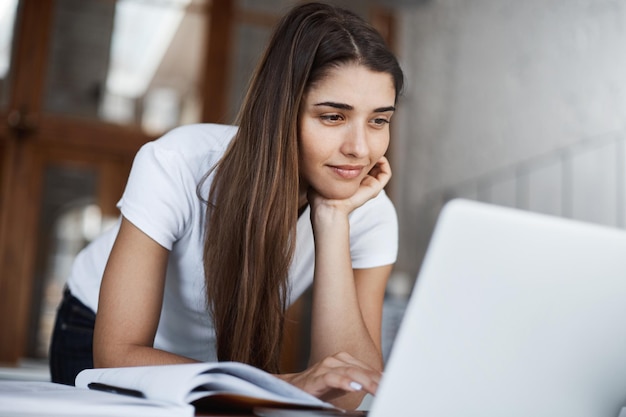 Gelukkige jonge vrouw die laptop gebruikt om door tonnen sociale media-berichten en foto's glimlachend te scrollen