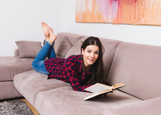 Gelukkige jonge vrouw die op het boek van de banklezing ligt