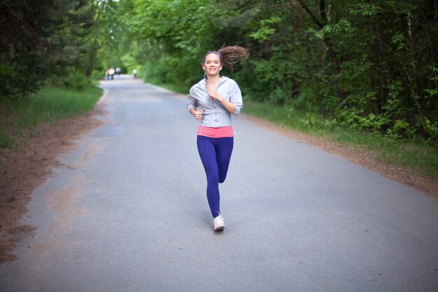 Gelukkige jonge vrouw joggen en lachend in het park