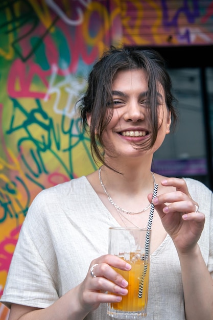 Gelukkige jonge vrouw met een glas limonade tegen een fel geschilderde muur