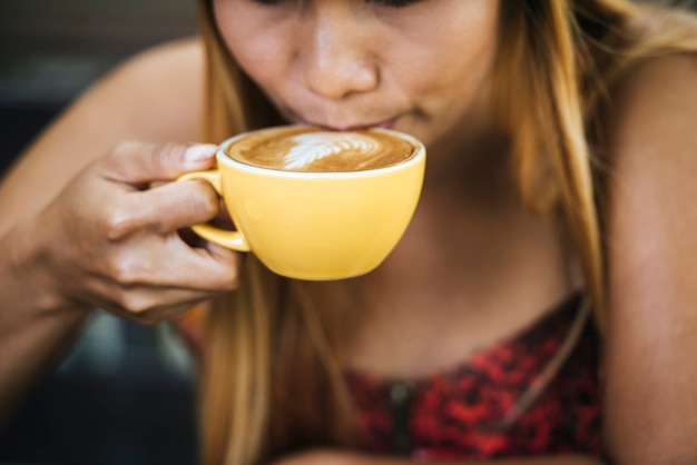 Gratis foto gelukkige jonge vrouw met lattekoffie in ochtend