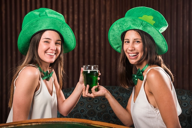 Gratis foto gelukkige jonge vrouwen die glas drank op sofa in ruimte houden