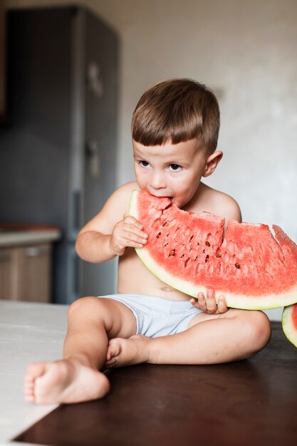 Gelukkige jongen die een reuzeplak van watermeloen eet