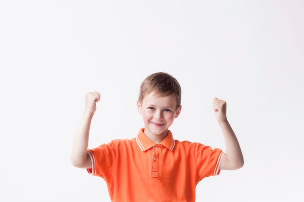 Gratis foto gelukkige jongen die vuist dichtklemmen die ja gebaar op witte muur maken