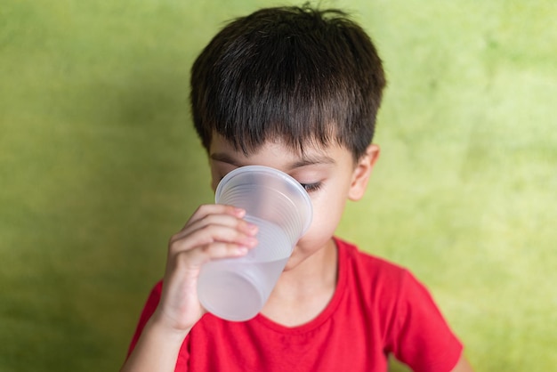 Gelukkige jongen met rood t-shirt drinkwater