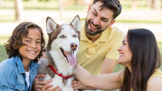 Gelukkige jongen poseren in het park met hond en ouders