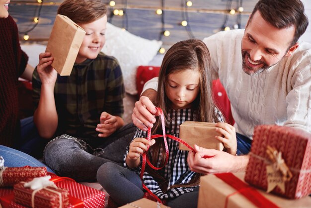Gelukkige kinderen die kerstcadeau met ouders openen