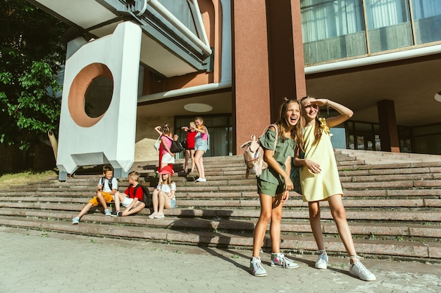 Gelukkige kinderen spelen in de stad straat in zonnige zomerdag voor modern gebouw. Groep gelukkige kinderen of tieners die samen plezier hebben. Concept van vriendschap, jeugd, zomer, vakantie.