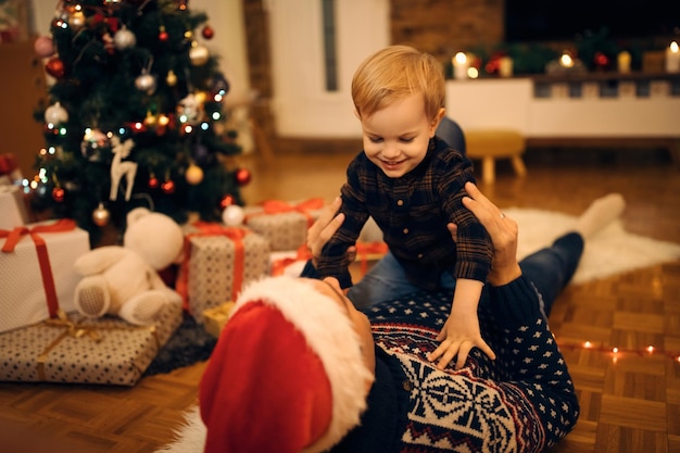 Gelukkige kleine jongen die plezier heeft met zijn vader op kerstavond thuis