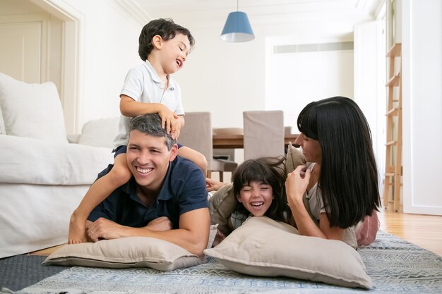 Gelukkige lachende ouders en twee kleine kinderen genieten van leuke tijd thuis