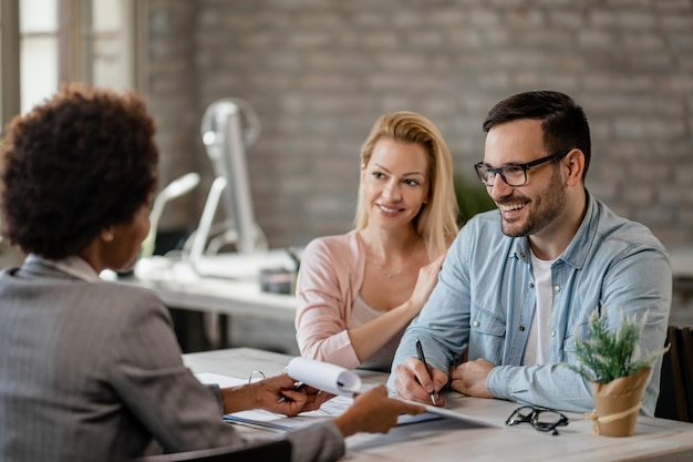 Gelukkige man die contract ondertekent terwijl hij met zijn vrouw een ontmoeting met financieel adviseur heeft