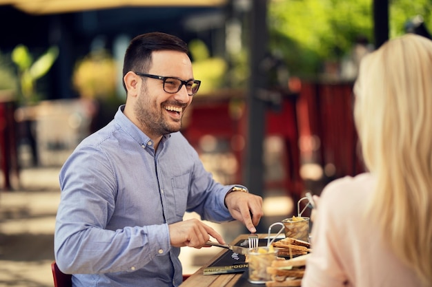 Gelukkige man die tijdens de lunch in een restaurant met zijn vriendin praat